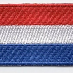 Peut inclure: Un patch brodé représentant le drapeau des Pays-Bas, avec les couleurs rouge, blanc et bleu.