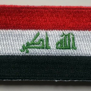 May include: An embroidered patch of the Iraqi flag. The flag is red, white, and black with a green Arabic inscription in the center.