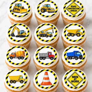 Puede incluir: Doce cupcakes cubiertos con decoraciones comestibles circulares que muestran vehículos de construcción, señales de tráfico y conos de seguridad. Los diseños incluyen una excavadora, apisonadora, grúa, camiones volquete, hormigonera y señales que dicen ROAD CONSTRUCTION AHEAD y MEN AT WORK, todo bordeado por rayas de peligro amarillas y negras.