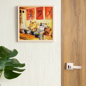 May include: A framed watercolor painting of three cats eating ramen in a restaurant. The restaurant has red signs with Japanese characters that read "東 ラ メ" (East Ramen).