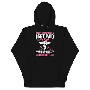 Può includere: Felpa con cappuccio nera con la scritta "DON'T MESS WITH ME I GET PAID TO STAB PEOPLE WITH SHARP OBJECTS" in bianco e rosa. Presenta grafiche di caduceo medico e siringa.