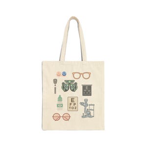 May include: Beige tote bag featuring various eye care illustrations, including eyeglasses, eye charts, and an eye exam machine. The bag has a simple design with a light-colored background and a pair of handles.