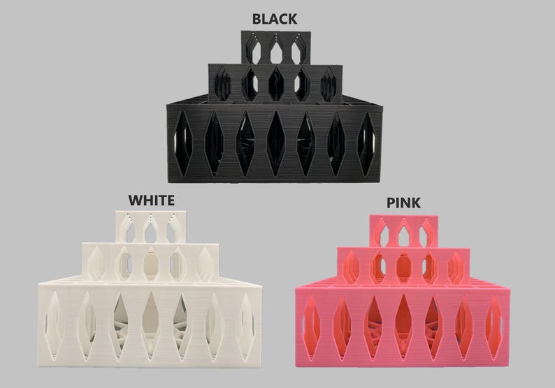 May include: Three tiered display stands in black, white, and pink. Each stand is made of plastic and has a diamond-shaped pattern. The stands are stacked on top of each other.