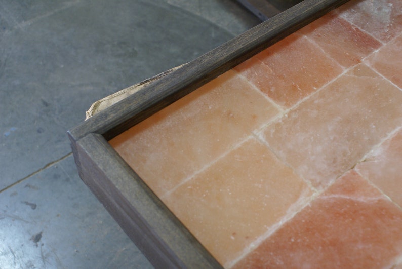 May include: A wooden frame with a salt tile insert. The tiles are a light pink color and are arranged in a grid pattern.