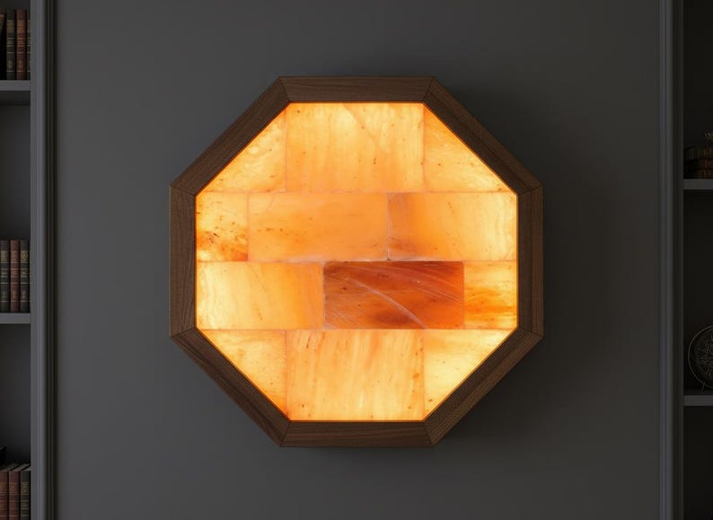 May include: An octagonal wall-mounted Himalayan salt lamp. The lamp features a wooden frame and is filled with illuminated orange salt crystals. The lamp is a decorative and functional item, providing a warm, ambient glow.