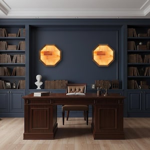 May include: A home office with dark blue walls and built-in bookshelves filled with books. A large wooden desk with a leather chair sits in front of the wall. Two octagonal, illuminated wall sconces and a bust sculpture add to the room's decor.