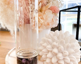 May include: A clear glass water bottle with a rose gold lid and base. The bottle contains amethyst crystals. The bottle is sitting on a wooden surface with a white decorative object.