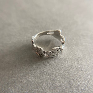 K&ouml;nnte beinhalten: Ein silberner Ring mit einem einzigartigen, strukturierten Design. Der Ring besteht aus einer Reihe von verbundenen, unregelm&auml;&szlig;igen Formen.