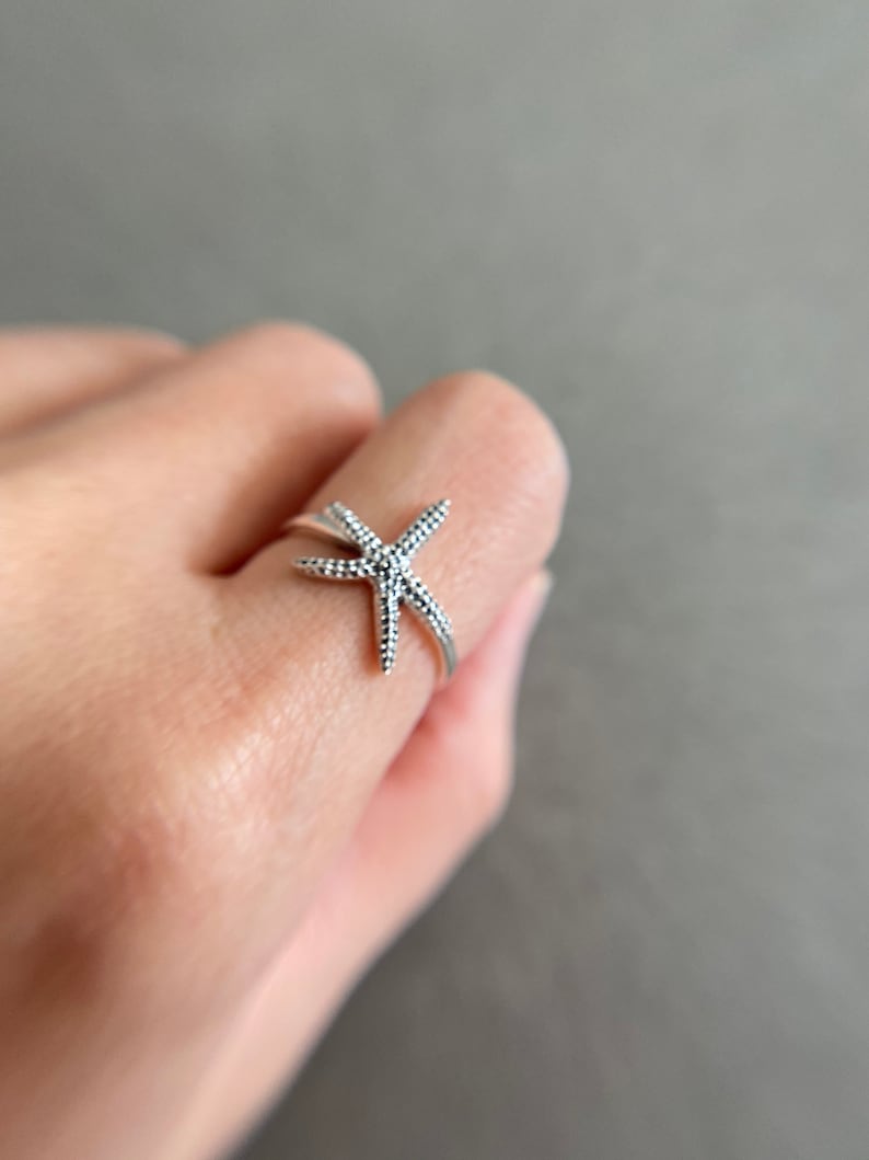 May include: A silver ring with a starfish design. The starfish is detailed with small dots.