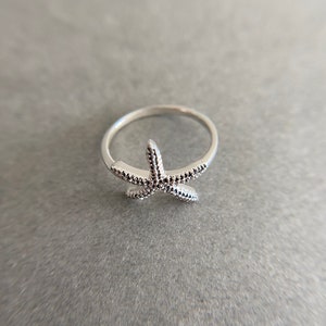 May include: A silver ring with a starfish design. The starfish is detailed with small dots.