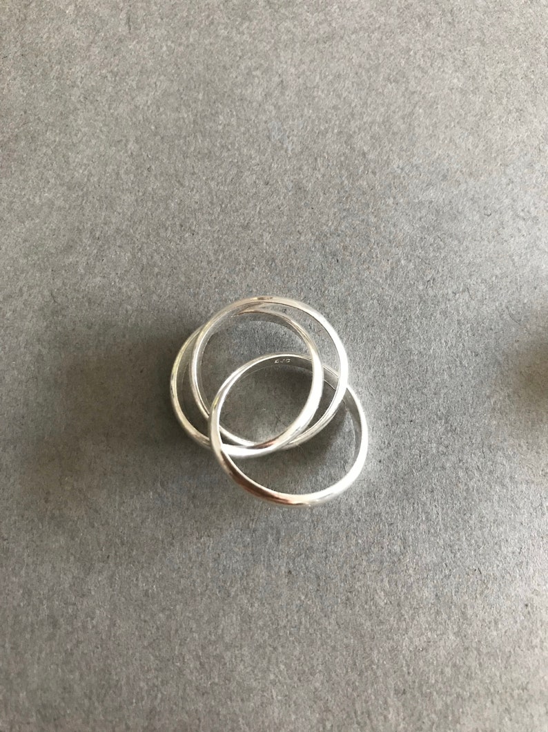 May include: Three interlocking silver rings, each with a smooth, rounded surface.