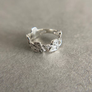 K&ouml;nnte beinhalten: Ein silberner Ring mit einem Design aus mehreren Engeln um das Band.