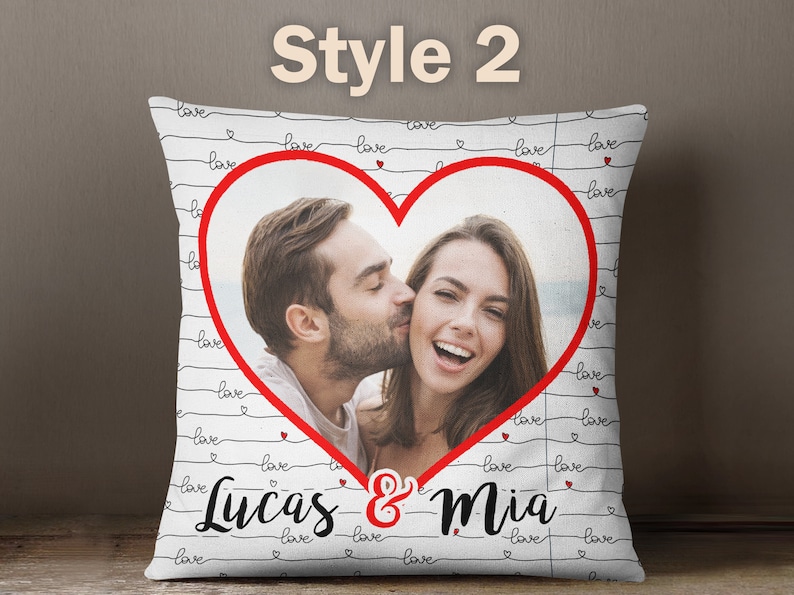 Puede incluir: Almohada blanca con l&iacute;neas negras y corazones rojos. La almohada tiene una foto de una pareja en forma de coraz&oacute;n con el texto "Lucas & Mia" debajo de la foto.