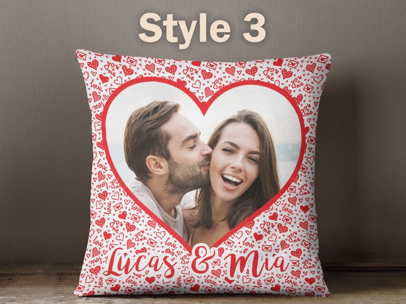 Puede incluir: Almohada blanca con un marco rojo en forma de coraz&oacute;n que contiene una foto de una pareja. El fondo de la almohada est&aacute; cubierto de corazones rojos y el texto "You & Me". El texto "Lucas & Mia" est&aacute; impreso debajo del coraz&oacute;n.