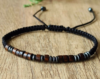 May include: A black cord bracelet with brown and black beads. The bracelet is adjustable and has a sliding knot.