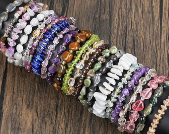 Puede incluir: Una pila de pulseras de piedras preciosas de colores, cada una con diferentes tipos de piedras y colores. Las pulseras están dispuestas en forma circular sobre una superficie oscura.