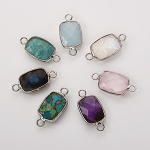 May include: Seven gemstone connectors in various colors, including green, blue, purple, and pink. Each rectangular stone is set in a silver-colored metal frame with a loop on each end for attaching to other jewelry components.