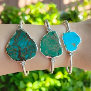 Puede incluir: Tres pulseras de plata con piedras turquesa. Las piedras son de diferentes formas y tamaños, y cada pulsera tiene un tono de turquesa diferente.