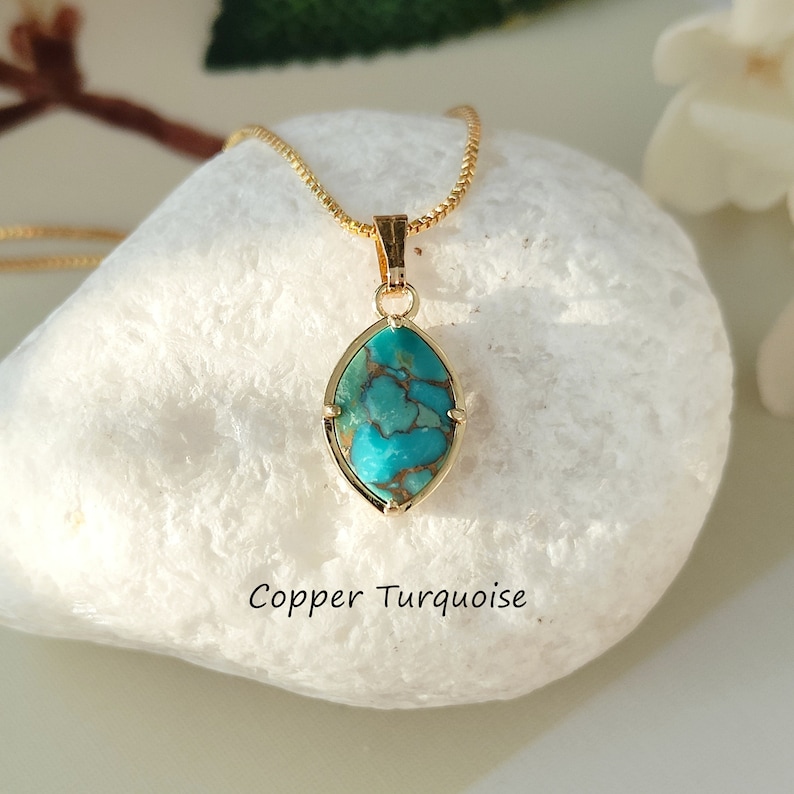 May include: A gold chain necklace with a copper turquoise pendant. The pendant is a marquise shape with a copper-colored matrix and a turquoise blue color.