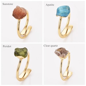 May include: Four gold-colored rings, each featuring a different gemstone: sunstone, apatite, peridot, and clear quartz. The gemstones are rough-cut and set on a minimalist, open-style band.
