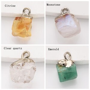 May include: Four different gemstone pendants with silver jump rings. The pendants are Citrine, Moonstone, Clear Quartz, and Emerald.
