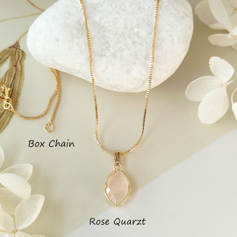May include: A gold chain necklace with a rose quartz pendant. The chain is a box chain style. The pendant is a light pink oval shape with a gold setting.