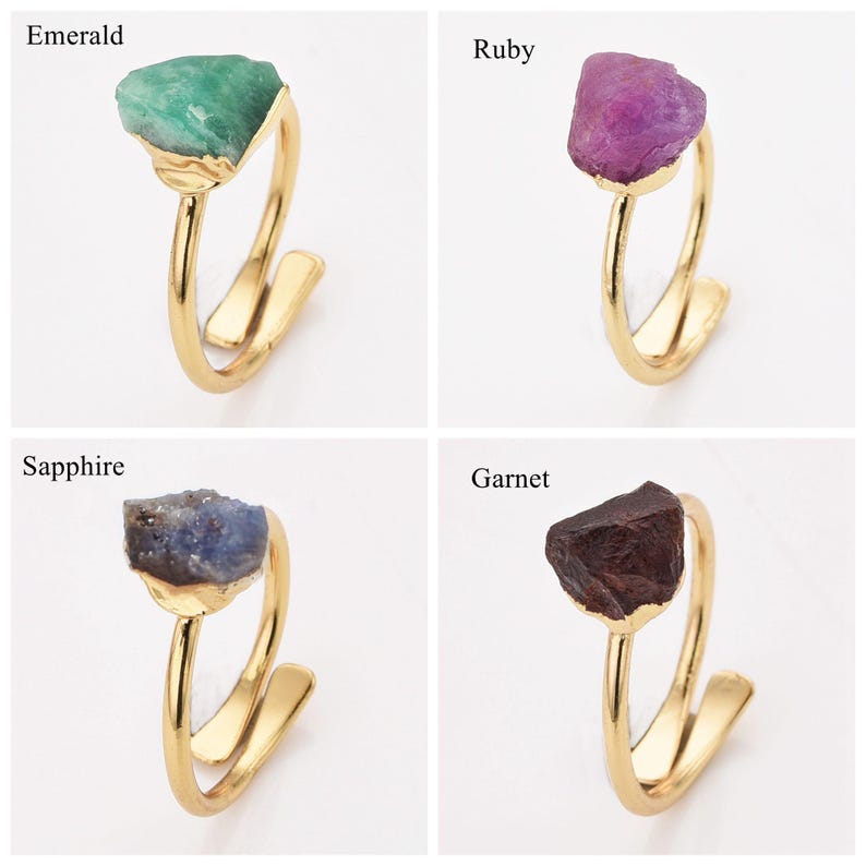 May include: Four gold-colored rings, each featuring a different gemstone: emerald, ruby, sapphire, and garnet. The gemstones are rough-cut and set on a minimalist, open-style band.