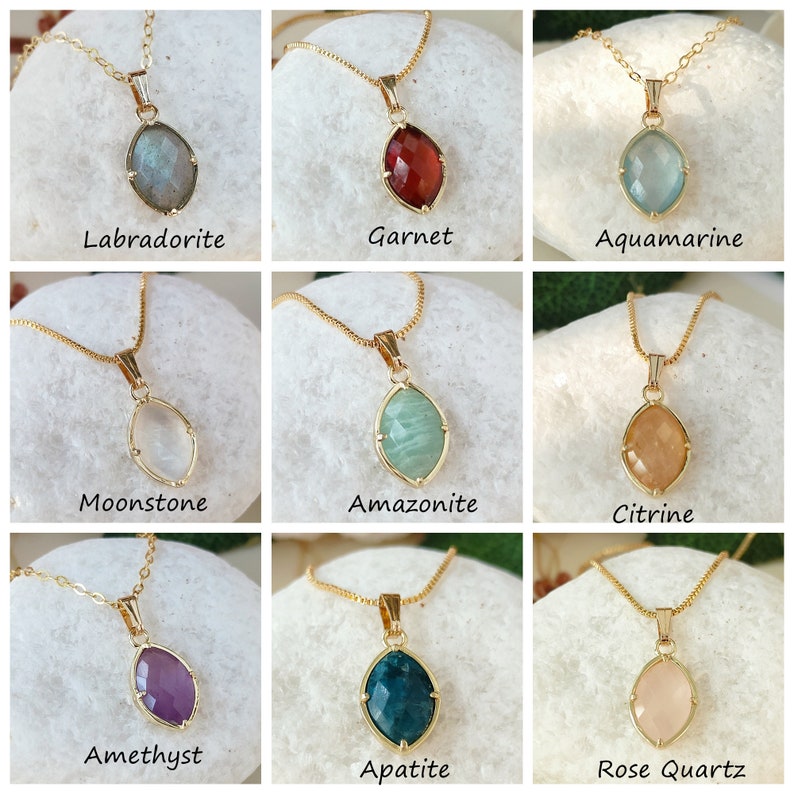 May include: Nine gold necklaces with different gemstone pendants. The gemstones are labradorite, garnet, aquamarine, moonstone, amazonite, citrine, amethyst, apatite, and rose quartz.