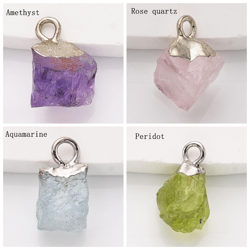 May include: Four silver charm pendants with different colored gemstones. The gemstones are amethyst, rose quartz, aquamarine, and peridot.
