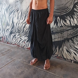 May include: A person wearing a black, gathered skirt with an elastic waistband.