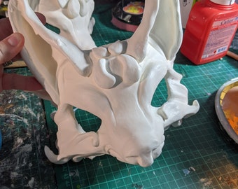 May include: White plaster mask with large, pointed ears and detailed facial features. The mask is unfinished and ready for painting.
