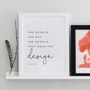 Pode incluir: Duas impressões emolduradas em uma prateleira branca. A moldura esquerda é branca com a citação "THE DETAILS ARE NOT THE DETAILS. THEY MAKE THE design" de Charles Eames. A moldura direita é preta com um mapa vermelho e branco da Escandinávia.