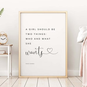 May include: A gold framed print with a white background and black text that reads "A girl should be two things: who and what she wants." with a small heart symbol and the text "COCO CHANEL" at the bottom.