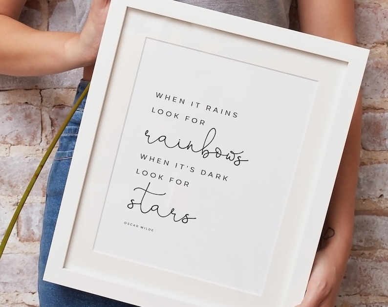 May include: White framed print with a black and white quote that reads "When it rains look for rainbows. When it's dark look for stars. Oscar Wilde."