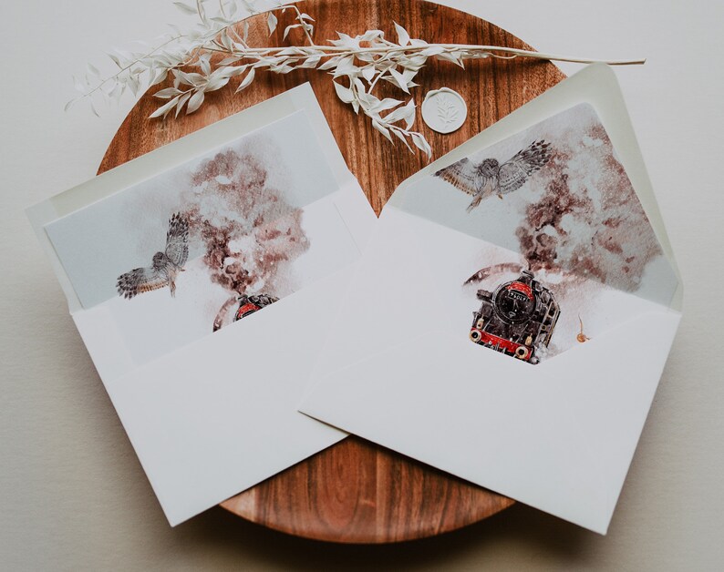 May include: Two white envelopes with watercolor illustrations of a steam train and an owl in flight. The envelopes are open, revealing the artwork inside. The envelopes are on a wooden surface with decorative elements.