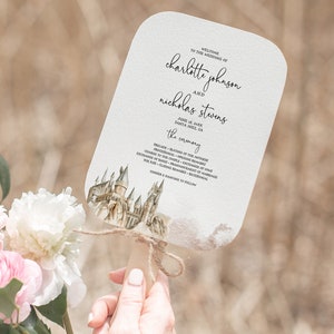 Peut inclure: Un éventail de programme de mariage blanc avec une illustration aquarelle du château de Poudlard. Le programme liste l'ordre de la cérémonie de mariage pour Charlotte Johnson et Nicholas Stevens le 12 juin 2021 à Santa Cruz, Californie.