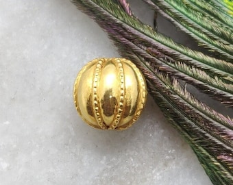 May include: A gold-colored metal bead with a ribbed design. The bead is round and has a smooth, shiny finish.