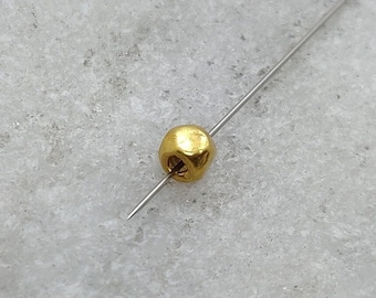 May include: A single gold bead on a thin wire.