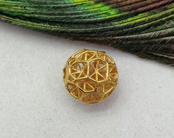 May include: A gold-colored, geometric, openwork sphere charm. The sphere is made of a delicate, intricate design with a starburst pattern.