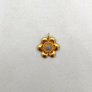 May include: A gold flower pendant with a blue gemstone in the center.
