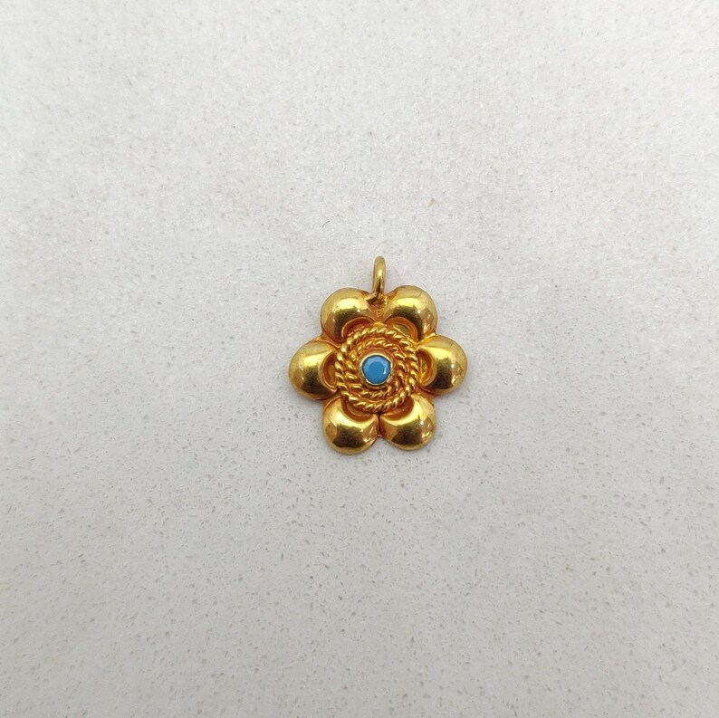 May include: A gold flower pendant with a blue gemstone in the center.