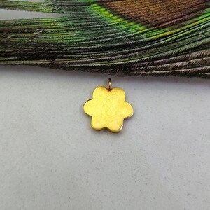 May include: A gold-colored flower charm pendant. The charm is made of metal and has a slightly textured surface.