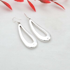 Op de afbeelding: Een paar zilveren oorhangers met een traanvorm en een open ontwerp. De oorhangers zijn gemaakt van sterling zilver en hebben een gepolijste afwerking.