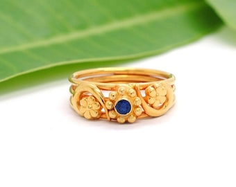 May include: A gold ring with a blue gemstone and floral designs.