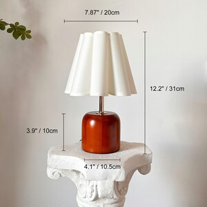 May include: A wooden table lamp with a white pleated lampshade. The lamp is 12.2 inches tall and the base is 4.1 inches wide.
