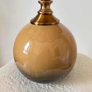 May include: A gold and brown glass table lamp with a round, ombre base and a decorative top.