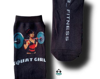 May include: A pair of black socks with a graphic of a woman lifting weights and the text "SQUAT GIRL". One sock has the text "B_FITNESS" on the side.