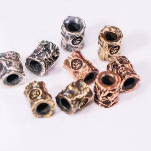 May include: A collection of eight metal beads with intricate designs. The beads are in various shades of silver, gold, and copper. Each bead has a unique pattern and a small hole in the center.