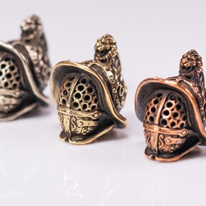 three Gladiator Helmet beads in brass, copper, and white brass finishes.