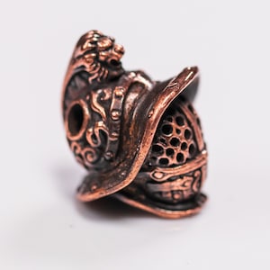 Red copper version of helmet bead highlighting sculptural depth and detail.